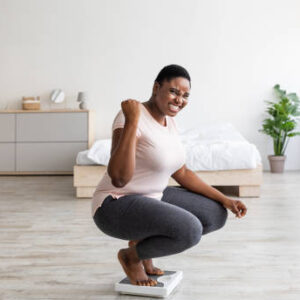 Happy woman smiling on the weight scale at home