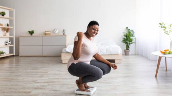 Happy woman smiling on the weight scale at home