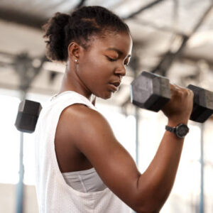 woman lifting arm weights in a gym because struggles don't define you, they refine you