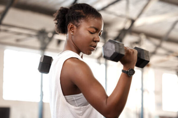 woman lifting arm weights in a gym because struggles don't define you, they refine you