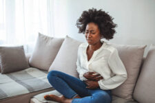 a beautiful woman on her home sofa suffering from endometriosis pain