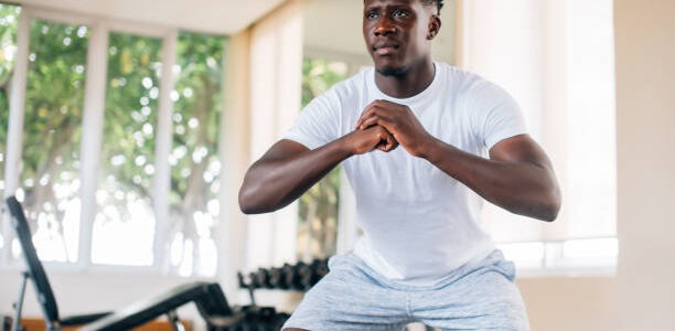 a focused fit gentleman in sportswear training others in training complexes