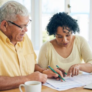 a senior couple sitting at a table doing paperwork and budgeting