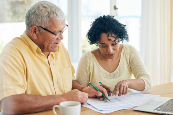 a senior couple sitting at a table doing paperwork and budgeting