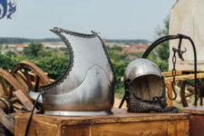 A closeup shot of an old metal helmet and breastplate outside on wood