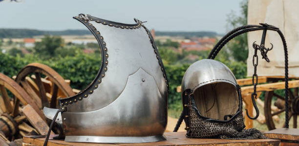 A closeup shot of an old metal helmet and breastplate outside on wood