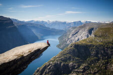 a person sitting on a Trolltunga rock above a Norwegian fjord.