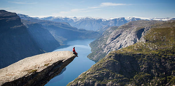 a person sitting on a Trolltunga rock above a Norwegian fjord.